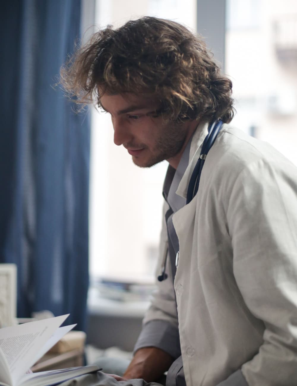 A doctor reading by a window